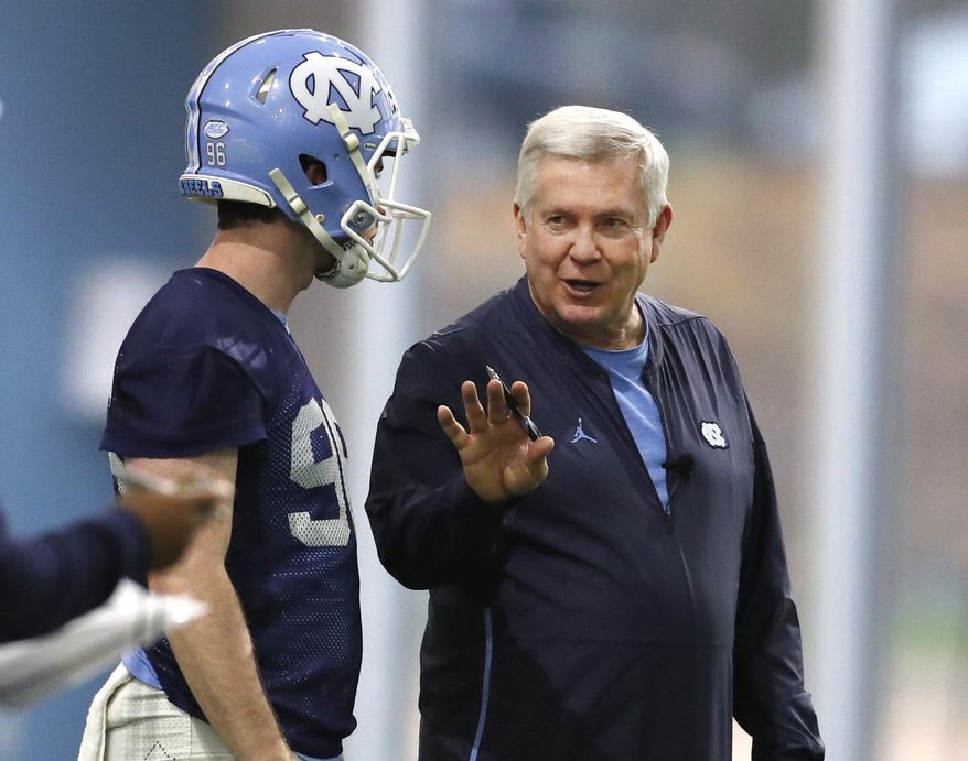 FILE - In this March 3, 2019, file photo, North Carolina head coach Mack Brown talks with Cooper Graham (96) during UNC&#39;s first spring football practice, in Chapel Hill, N.C. Brown is savoring his return to coaching in a second stint with the Tar Heels. Brown had worked in broadcasting in the years since his departure from Texas after the 2013 season. But he says the time away rejuvenated him for his chance to return to the sideline. Now he’s trying to stabilize a UNC program that has won two Atlantic Coast Conference games over the past two seasons. (Ethan Hyman/The News &amp;amp; Observer via AP, File)