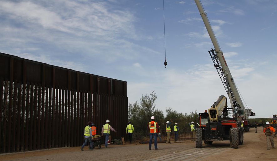 Workers break ground on new border wall construction about 20 miles west of Santa Teresa, New Mexico, Aug. 23, 2019. The wall visible on the left was built in 2018 with money allocated by Congress, while the new construction is funded by money reallocated from Department of Defense funding. (AP Photo/Cedar Attanasio)