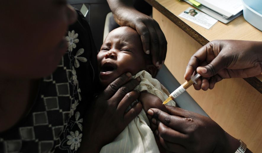 FILE - In this Oct. 30, 2009 file photo, a mother holds her baby receiving a new malaria vaccine as part of a trial at the Walter Reed Project Research Center in Kombewa in Western Kenya. The World Health Organization said Thursday Aug. 22, 2019, it’s theoretically possible to wipe out malaria, but probably not with the flawed vaccine and other control methods being used at the moment. (AP Photo/Karel Prinsloo, File)