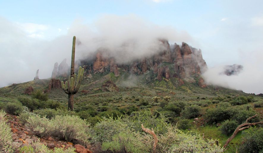 FILE - In this Jan. 29, 2015 file photo, low-hanging winter clouds hug part of Superstition Mountain in Lost Dutchman State Park in Apache Junction, Ariz. Summer is a different story. Authorities said Friday, Aug. 23, 2019 that 44 members of an out-of-state hiking group had to be rescued from the Phoenix trail after being overcome by heat that reached 106 degrees Fahrenheit Thursday. Superstition Fire &amp;amp; Medical District officials say two hikers were flown out by helicopter while others were able to walk back down with assistance. (AP Photo/Ted Shaffrey, File)