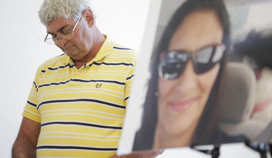 FILE - In this July 25, 2019 file photo John Nicholas, brother of Rhogena Nicholas, lowers his head next to a photo of his sister during a news conference in Houston. A former Houston police officer has been charged with felony murder in connection with a deadly January drug raid that killed a couple and injured several officers, prosecutors announced Friday, Aug. 23. Killed in the shooting were 58-year-old Rhogena Nicholas and 59-year-old Dennis Tuttle.(Elizabeth Conley/Houston Chronicle via AP)