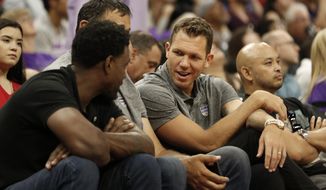 FILE - In this July 1, 2019, file photo, Sacramento Kings head coach Luke Walton talks with former Sacramento Kings player Chris Webber, left, as Kings general manager Vlade Divac, obscured at center, looks on during the first half of an NBA basketball summer league gamebetween the Kings and Golden State Warriors in Sacramento, Calif. The Sacramento Kings and the NBA have announced that after a thorough investigation there isn’t enough evidence to support allegations that new coach Luke Walton sexually assaulted a woman. The team and league began a joint investigation in April following a lawsuit filed in Los Angeles by former sportscaster Kelli Tennant, who “elected not to participate in the investigation. Based on this and the available evidence, the investigators determined that there was not a sufficient basis to support the allegations made against Coach Walton,” the Kings announced in a joint statement with the NBA. (AP Photo/Rich Pedroncelli, File)