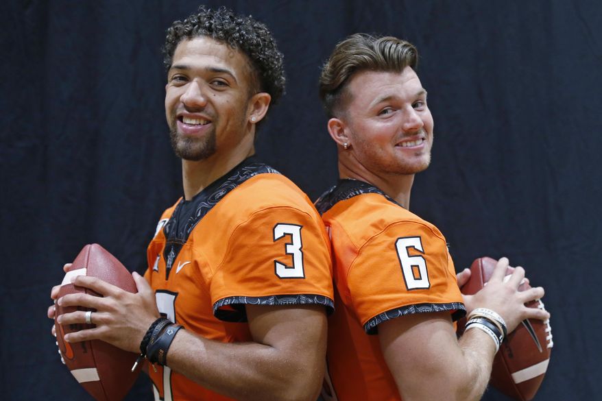 FILE - In this Saturday, Aug. 3, 2019, file photo, Oklahoma State quarterbacks Spencer Sanders, left, and Dru Brown pose for a photo during the NCAA college football team's media day in Stillwater Okla. Oklahoma State hasn’t named a starting quarterback yet for its season opener next Friday night at Oregon State, as coach Mike Gundy continues to evaluate redshirt freshman Spencer Sanders and Hawaii grad transfer Dru Brown for the job. At this point, it seems likely that both will see action. (AP Photo/Sue Ogrocki, File)