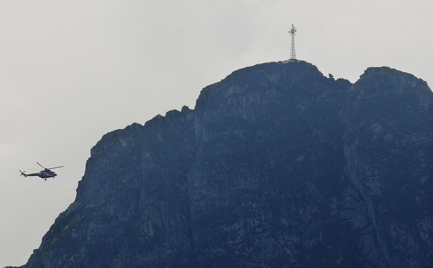 Rescuers in a helicopter checking the slopes of the Giewont peak for missing persons and anyone who might need help in the Tatra Mountains in Poland, Friday, Aug. 23, 2019. Three people are still missing in southern Poland after a deadly thunderstorm with multiple lightning strikes hit the Tatra Mountains, killing five people and injuring over 150. (AP Photo/Bartlomiej Jurecki)