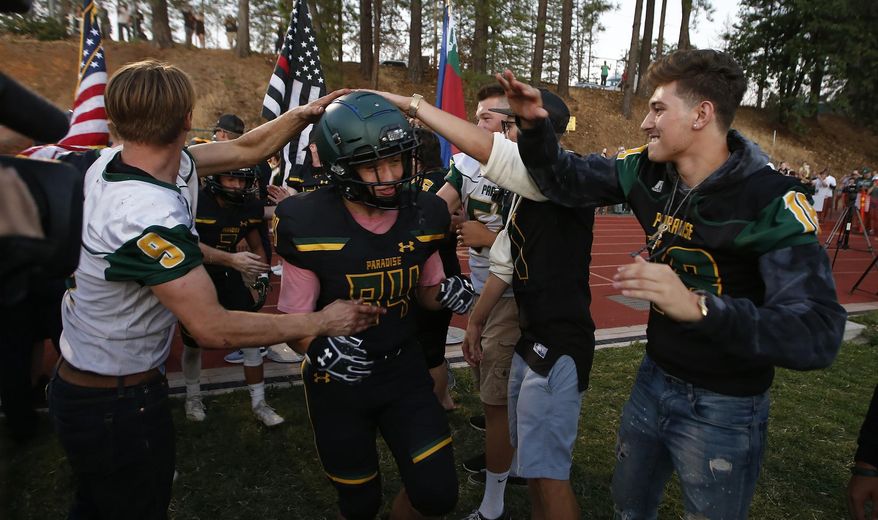 Paradise tight end Jacob Duncan runs through a tunnel of former players during the opening ceremony of their high school football game against Williams, in Paradise, Calif., Friday Aug. 23, 2019. This is the first game for the school since a wildfire in November killed multiple people and destroyed nearly 19,000 buildings, including the homes of most of the Paradise players. (AP Photo/Rich Pedroncelli)