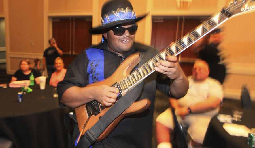 Zayne Harshaw, founder of Blue Spectrum, performs at the ARC of Ohio People First dance on July 12, 2019 at the Nationwide Hotel and Conference Center in Lewis Center, Ohio. When Zayne was 4, he was formally diagnosed with autism. Now 24, Zayne is playing paid gigs with his Blue Spectrum band at music festivals and other events across the country, and proving those doctors wrong with a gift he developed in the dark. (Doral Chenoweth III/The Columbus Dispatch via AP)