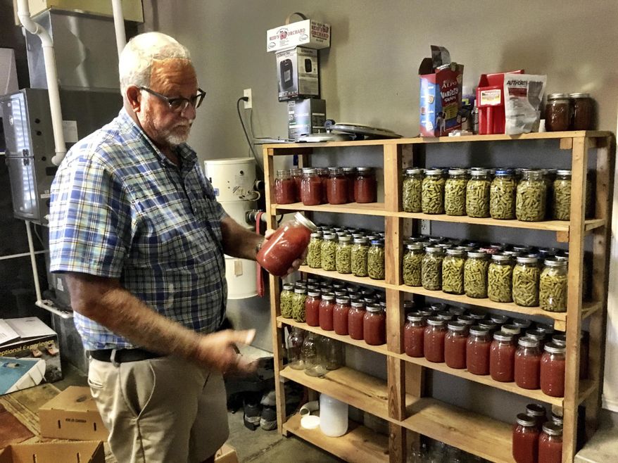 Neil Rudy pulls a jar of tomato juice off a shelf in his garage in West Daviess County, KY., where he keeps the canned vegetables that he and his wife, Vicky, store. The Rudys canned tomato juice and green beans this years, combining for nearly 200 quarters that will last through until next season. (Don Wilkins/The Messenger-Inquirer via AP)