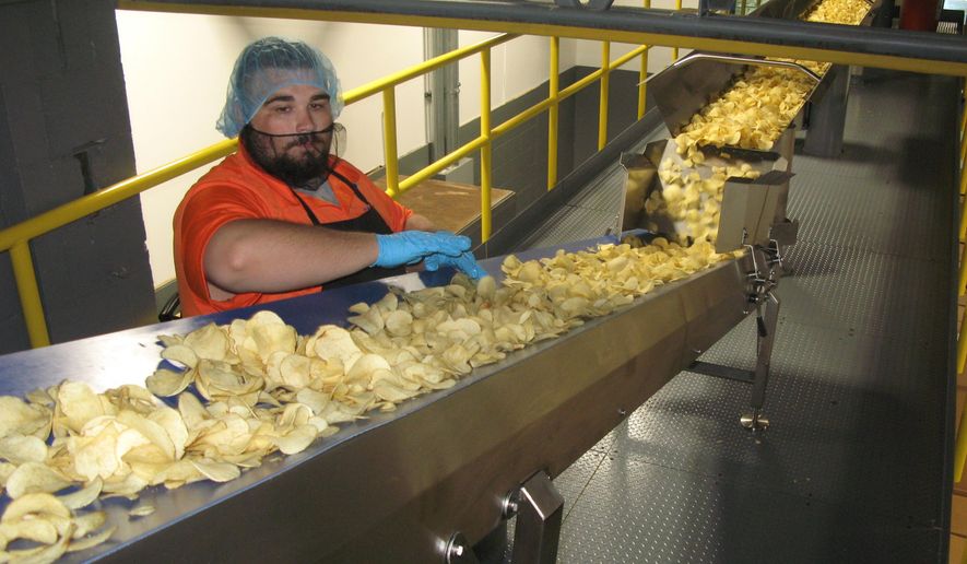 In this Thursday, Aug. 8, 2019 photo, on the catwalk level, Mister Bee employee Wesley "Chunk" Canterbury performs another check for defects at West Virginia Potato Chip Co. in Parkersburg, W.Va. Mister Bee potato chips have been made in Parkersburg for nearly 70 years, but today the process is more efficient than ever. (Evan Bevins/News and Sentinel via AP)