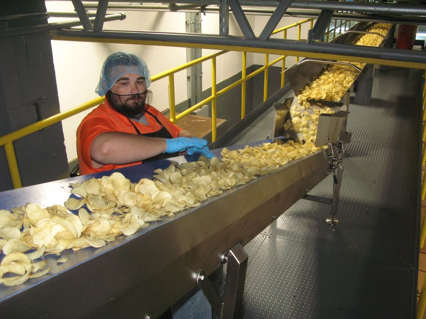 In this Thursday, Aug. 8, 2019 photo, on the catwalk level, Mister Bee employee Wesley "Chunk" Canterbury performs another check for defects at West Virginia Potato Chip Co. in Parkersburg, W.Va. Mister Bee potato chips have been made in Parkersburg for nearly 70 years, but today the process is more efficient than ever. (Evan Bevins/News and Sentinel via AP)