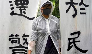 A woman wears a raincoat stands next to banners that read &amp;quot;The duty fulfilled by the police belongs to the people&amp;quot; as people take part in a rally to support the Hong Kong&#39;s Police at Edinburgh Place in Hong Kong, Sunday, Aug. 25, 2019. (AP Photo/Vincent Yu)