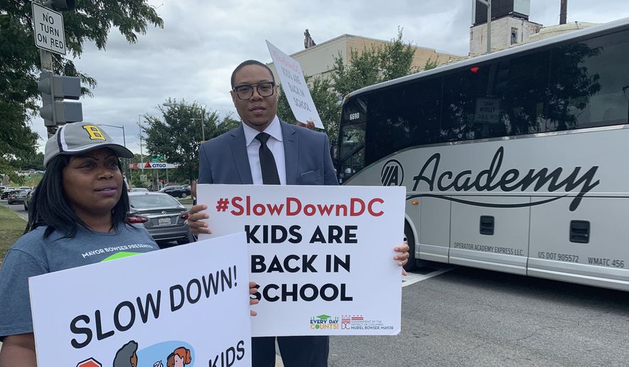 D.C. Public Schools Chancellor Lewis D. Ferebee and parent Isha Lee tell drivers to slow down at the intersection of Pennsylvania and Minnesota avenues in Southeast on Monday’s first day of school as part of the Safe Passage and Slow Down campaign. (Sophie Kaplan/The Washington Times)