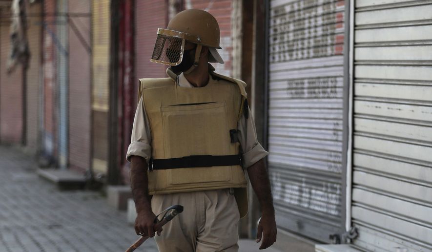 In this Thursday, Aug. 22, 2019 photo, a Kashmiri policeman guards outside a closed shop in Srinagar, Indian-controlled Kashmir. Thirty Kashmiri police officers who spoke on the condition of anonymity fearing retribution from their superiors told The Associated Press that they have been sidelined and in some cases disarmed by New Delhi-based authorities since the government of Prime Minister Narendra Modi downgraded Jammu and Kashmir from a state into two federally administered territories, tightening its grip on the restive region. (AP Photo/Mukhtar Khan)