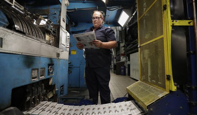In this Tuesday, Aug. 6, 2019, photo, press operator Robin Yeager looks over the registration of a newspaper in Youngstown, Ohio. The Youngstown paper announced in June it would cease publication Saturday, Aug. 31, because of financial struggles, but the paper will be printed by the Tribune Chronicle, which has bought The Vindicator name, subscriber list and website from owners of the Youngstown publication. (AP Photo/Tony Dejak)