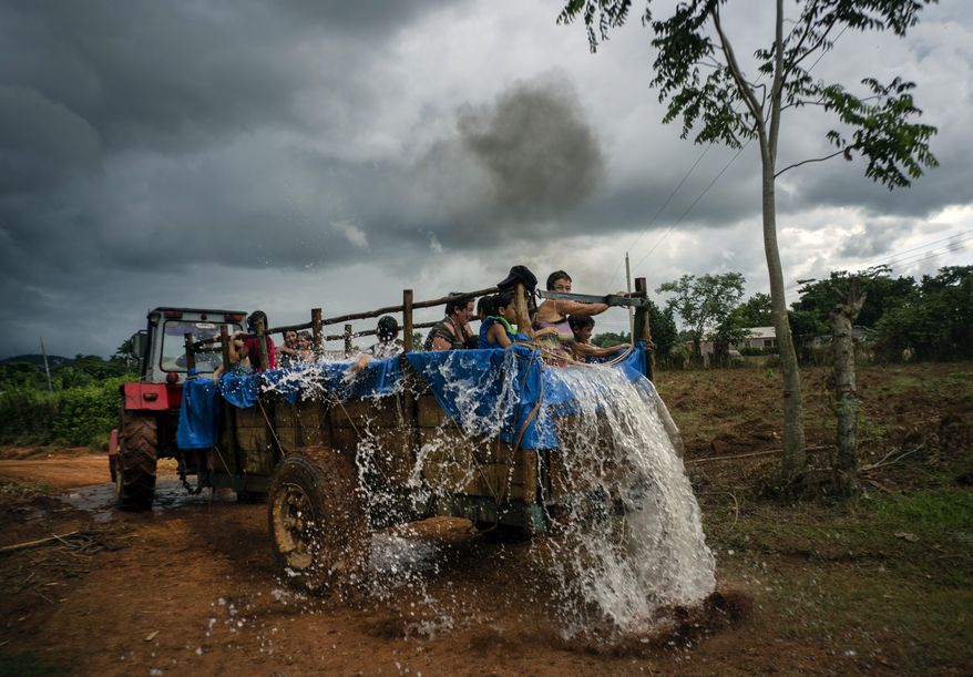 In this Aug. 24, 2019 photo, a tractor pulls a trailer that was converted into a swimming pool as it drives along the roads of El Infernal neighborhood in San Andres in the province of Pinar del Río, Cuba. The idea for the mobile tractor-pool was hatched by local parents, to make their kids happy and fight the harsh Caribbean heat. (AP Photo/Ramon Espinosa)