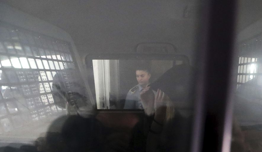 A 19-year old British woman, is seen inside a police vehicle with head covered, as she leaves the Famagusta court in Paralimni, Cyprus, Tuesday, Aug. 27, 2019, after pleading not guilty to a public mischief charge. The Cyprus court judge set the start of the trial for Oct. 2 and released the woman on bail, finding it "proper and fair" to do so after having spent nearly two months in police detention. (AP Photo/Petros Karadjias)