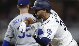 San Diego Padres&#39; Eric Hosmer, right, reacts after hitting an RBI single as Los Angeles Dodgers right fielder Cody Bellinger stands on first base, left, during the fourth inning of a baseball game, Monday, Aug. 26, 2019, in San Diego. (AP Photo/Gregory Bull)