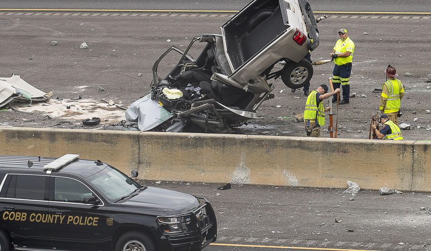 Cobb County Fire Fighters work to clear the wreckage from a deadly scene where a pick-up truck ran through a retaining wall and plunged onto Interstate 75 North near the I-285 exchange in Vinnings, Ga., Monday, Aug. 26, 2019. (Alyssa Pointer/Atlanta Journal-Constitution via AP)