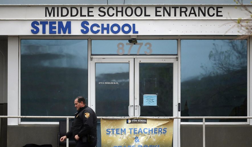 FILE - In this May 8, 2019, file photo, a Douglas County, Colo., Sheriff's Department deputy walks past the doors to the STEM School Highlands Ranch, in Highlands Ranch, Colo. A private security guard who officials say accidentally fired at a deputy and ended up wounding a student during a shooting at the school on May 7, 2019 was not supposed to be armed, The Colorado Sun reported. (AP Photo/David Zalubowski, File)