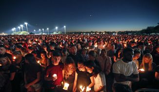 In this Feb. 15, 2018, file photo people attend a candlelight vigil for the victims of the shooting at Marjory Stoneman Douglas High School in Parkland, Fla. Parents whose children were killed or wounded during the Parkland high school massacre asked the Florida Supreme Court on Wednesday, Aug. 28, 2019, to rule that each pull of the trigger was a separate occurrence for which the Broward County School Board should be held liable. (AP Photo/Gerald Herbert, file) **FILE**