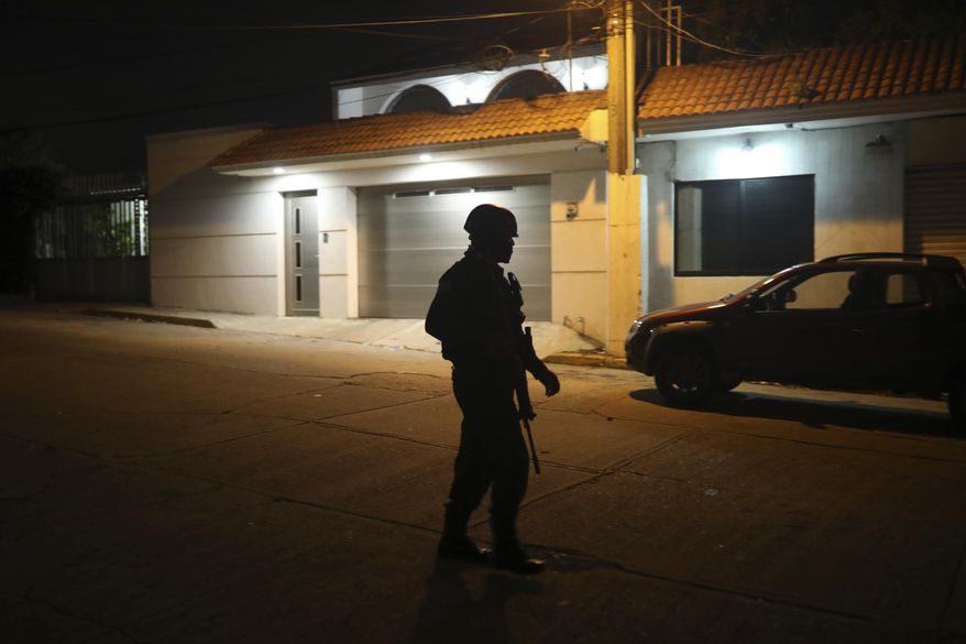 A police officer walks close to the scene outside a bar where more than 20 people died in an overnight attack, in Coatzacoalcos, Mexico, early Wednesday, Aug. 28, 2019. President Andres Manuel Lopez Obrador said Wednesday "the criminals went in, closed the doors, the emergency exits, and set fire to the place." (AP Photo/Felix Marquez)