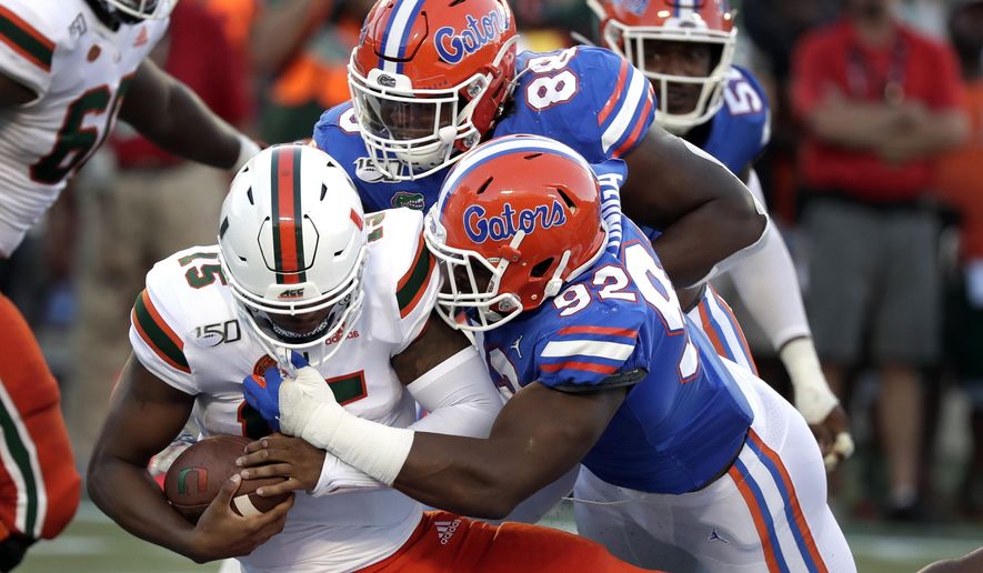 FILE - In this Aug. 24, 2019, file photo, Miami quarterback Jarren Williams, left, is sacked by defensive linemen Adam Shuler, center, and Jabari Zuniga, right, during the first half of an NCAA college football game in Orlando, Fla. This is the time of year when the Southeastern Conference usually validates its claim as the best league in college football by dominating neutral-site nonconference matchups. The SEC is 21-6 in regular-season nonconference games against Power Five opponents at neutral sites since 2012. (AP Photo/John Raoux, File)