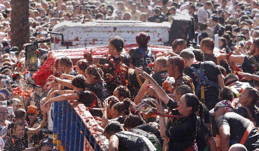 Revellers throw tomatoes at each other during the annual "Tomatina", tomato fight fiesta in the village of Bunol near Valencia, Spain, Wednesday, Aug. 28, 2019. (AP Photo/Alberto Saiz)