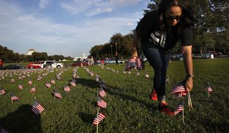 Patrice Sullivan, whose boyfriend, a Marine, died from suicide, helps to remove 5,000 small U.S. flags representing suicides of active and veteran members of the military line the National Mall, Wednesday, Oct. 3, 2018, in an action by the Iraq and Afghanistan Veterans of America (IAVA), in Washington. (AP Photo/Jacquelyn Martin)