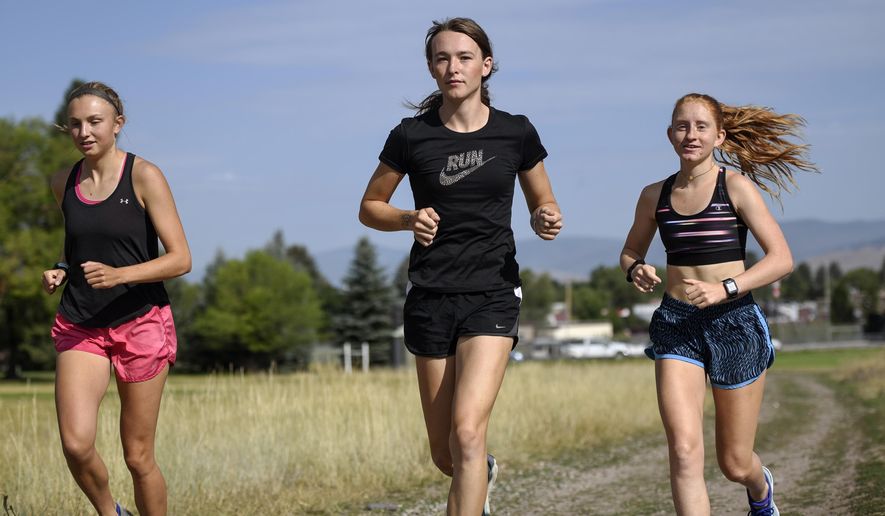 In this Aug. 15, 2019, file photo, University of Montana cross country runner June Eastwood, center, warms up with her teammates at Campbell Park in Missoula, Mont. (Rachel Leathe/Bozeman Daily Chronicle via AP) ** FILE **