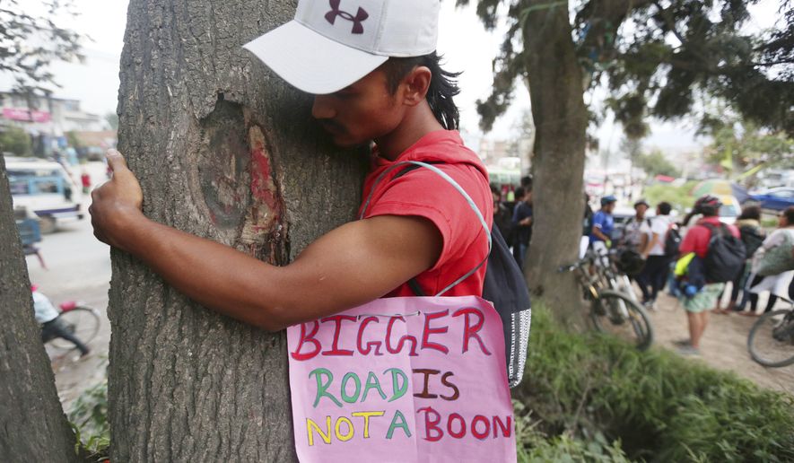 An activist hugs a tree during a protest against government plans to cut down trees to widen a key road that circles the city in Kathmandu, Nepal, Thursday, Aug. 29, 2019. More than 200 people participated in the protest. (AP Photo/Niranjan Shrestha)