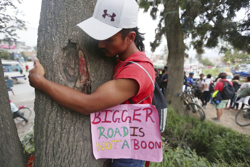 An activist hugs a tree during a protest against government plans to cut down trees to widen a key road that circles the city in Kathmandu, Nepal, Thursday, Aug. 29, 2019. More than 200 people participated in the protest. (AP Photo/Niranjan Shrestha)