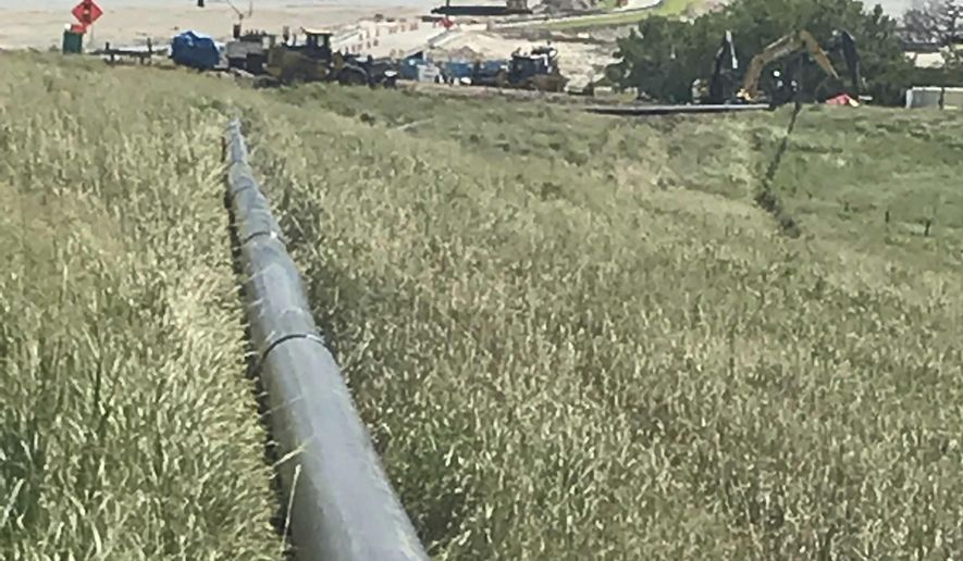 In this Aug. 14, 2019 photo, pipelines are installed under the Niobrara River in Boyd County, Neb. Drinking water is being restored in Boyd County after a disastrous flood washed out a water main in March.The Omaha World-Herald reports that workers began installing a new pipe beneath the Niobrara River on Tuesday, Aug. 27. (Paul Hammel/Omaha World-Herald via AP)