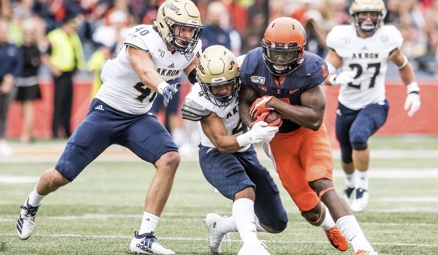 Illinois's Ricky Smalling (4) is tackled by Akron's John Lasso, left, and Dylan Meeks after making a catch in the first half of a NCAA college football game, Saturday, Aug. 31, 2019, in Champaign, Ill. (AP Photo/Holly Hart)