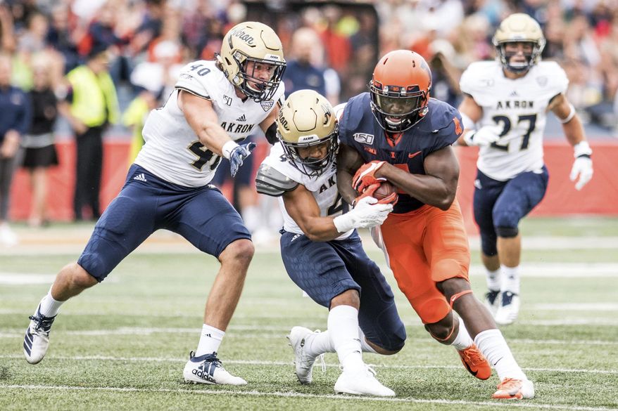 Illinois's Ricky Smalling (4) is tackled by Akron's John Lasso, left, and Dylan Meeks after making a catch in the first half of a NCAA college football game, Saturday, Aug. 31, 2019, in Champaign, Ill. (AP Photo/Holly Hart)