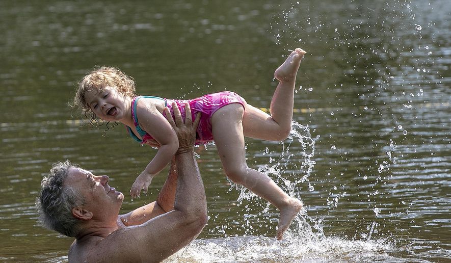 In this July 3, 2019 file photo, Robert Megna, of New Haven, gives a lift to daughter Catherine, 3, while swimming at Wharton Brook State Park in Wallingford, Conn. Hundreds of thousands more people are visiting Connecticut's beaches and parks in 2019, due in part to a two-year-old program that provides free admittance for vehicles with a state license plate. (Dave Zajac/Record-Journal via AP, File)