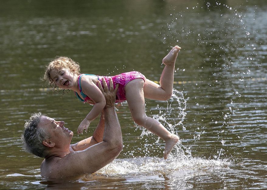 In this July 3, 2019 file photo, Robert Megna, of New Haven, gives a lift to daughter Catherine, 3, while swimming at Wharton Brook State Park in Wallingford, Conn. Hundreds of thousands more people are visiting Connecticut's beaches and parks in 2019, due in part to a two-year-old program that provides free admittance for vehicles with a state license plate. (Dave Zajac/Record-Journal via AP, File)