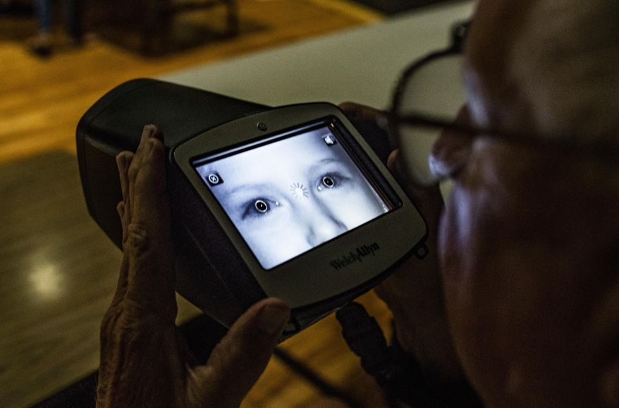 In this Friday, Aug. 23, 2019 photo, Deon Benson of the Smiths Grove Lion's Club uses a Spot Vision Screener to scan a child's eyes testing for potential vision issues at North Warren Elementary School in Bowling Green, Ky.. (Austin Anthony/Daily News via AP)
