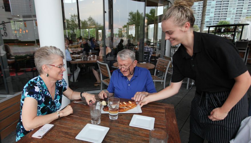 In this Friday, Aug. 23, 2019 photo, Bill and Jennifer Casto celebrate their anniversary in Columbus, Ohio, the way they have spent most nights of their 24-year marriage, by dining out at a restaurant. Sarah Curry serves them at Milestone 229, which is where they have celebrated anniversaries in recent years. (Doral Chenoweth III/The Columbus Dispatch via AP)