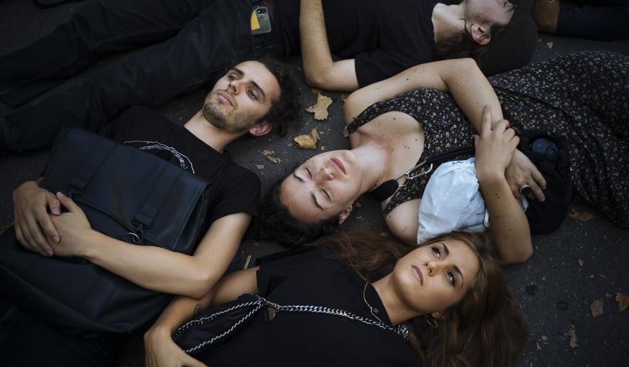 Extinction Rebellion activists lay on the ground as they protest in Paris, Saturday, Aug. 31, 2019, to call on Brazil's President Jair Bolsonaro to act to protect the Amazon rainforest. (AP Photo/Kamil Zihnioglu)