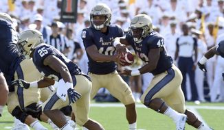 Navy quarterback Malcolm Perry hands off to Nelson Smith in the first quarter of an NCAA college football game against Holy Cross, Saturday, Aug. 31, 2019, in Annapolis, Md. (Paul W. Gillespie/Capital Gazette via AP)