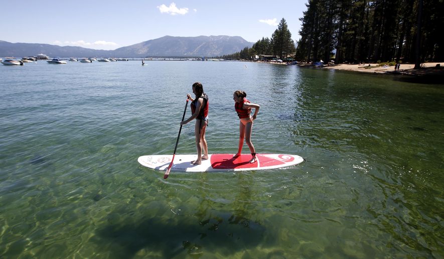 FILE - In this Aug. 20, 2019, file photo, Freya Mayo, left, and her sister Evie, of London, England, try out a paddle board on Lake Tahoe near South Lake Tahoe, Calif. The fallout from humanity's addition to plastics is showing up in the waters of Lake Tahoe. Scientists detected microplastics at several locations around the lake for the first time this year and are working to understand what that means for human health and the environment of the Tahoe Basin. (AP Photo/Rich Pedroncelli, File)