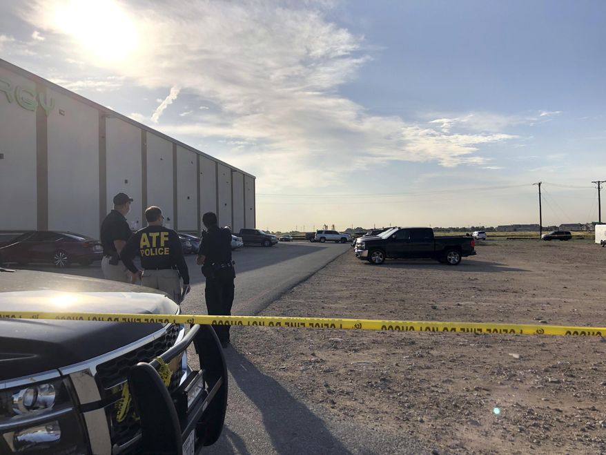 Bureau of Alcohol, Tobacco, Firearms and Explosives agents speak with a local police officer in a gravel lot next to an Odessa, Texas, movie theater Sunday, Sept. 1, 2019, where authorities say the suspected shooter in Saturday's rampage was killed. The death toll in the West Texas shooting rampage increased to Sunday as authorities investigated why a man stopped by state troopers for failing to signal a left turn opened fire on them and fled, shooting over a dozen people as he drove before being killed by officers outside a movie theater. (AP Photo/Jake Bleiberg)