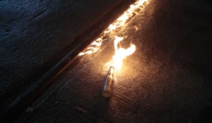 A molotov cocktail hurled by a protestor burns on a street in Hong Kong, Saturday, Aug. 31, 2019. A large fire blazed across a main street in Hong Kong on Saturday night, as protesters made a wall out of barricades and set it afire. Hundreds of protesters gathered behind the fire, many pointing laser beams that streaked the night sky above them. (AP Photo/Jae C. Hong)
