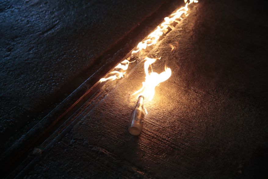 A molotov cocktail hurled by a protestor burns on a street in Hong Kong, Saturday, Aug. 31, 2019. A large fire blazed across a main street in Hong Kong on Saturday night, as protesters made a wall out of barricades and set it afire. Hundreds of protesters gathered behind the fire, many pointing laser beams that streaked the night sky above them. (AP Photo/Jae C. Hong)