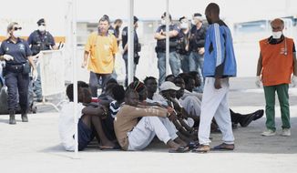 Migrants sits after disembarking from the German rescue boat Eleonore in the port of Pozzallo, Sicily, Southern Italy, Monday, Sept. 2, 2019. Italy’s interior minister is vowing to make the charity boat with some 100 rescued migrants aboard pay dearly for docking in Sicily in defiance of a government ban. (Francesco Ruta/ANSA via AP)