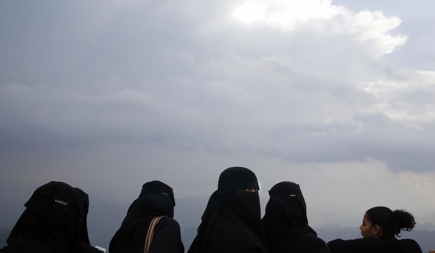 In this Thursday, Aug. 22, 2019 photo, Saudi tourists take in the view from a mountain during the al-Soudah festival in Abha, southwest Saudi Arabia. A festival atop this chain of mountains drew a medley of yoga enthusiasts, extreme adventure seekers, tourists and traditional Saudi families -- many wearing colorful flower crowns native to the region as the kingdom looks for ways to revamp its image and build up tourism. (AP Photo/Amr Nabil)