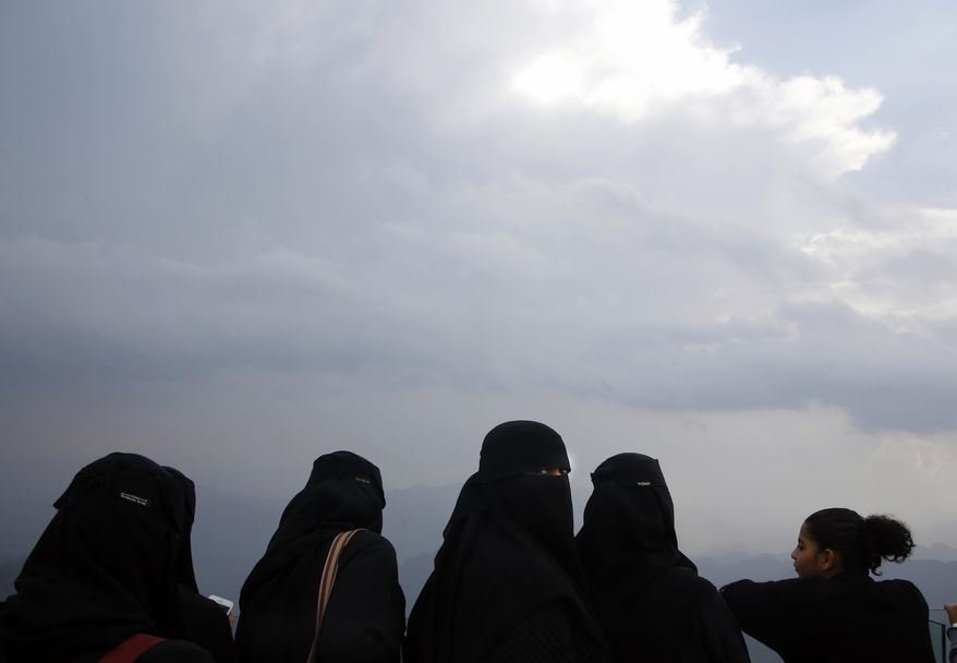 In this Thursday, Aug. 22, 2019 photo, Saudi tourists take in the view from a mountain during the al-Soudah festival in Abha, southwest Saudi Arabia. A festival atop this chain of mountains drew a medley of yoga enthusiasts, extreme adventure seekers, tourists and traditional Saudi families -- many wearing colorful flower crowns native to the region as the kingdom looks for ways to revamp its image and build up tourism. (AP Photo/Amr Nabil)