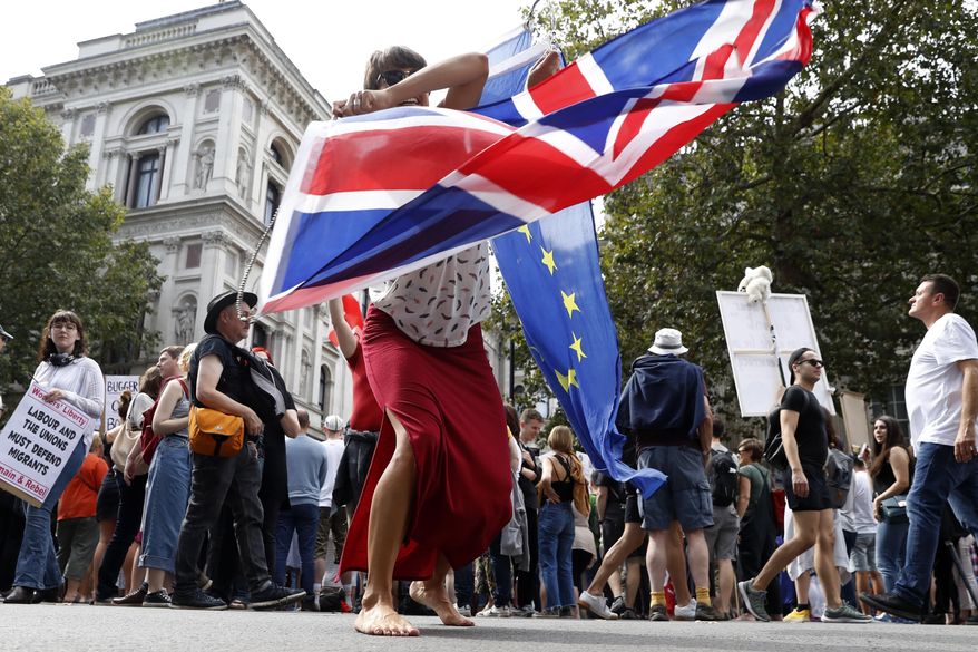 An anti Brexit protester waves the flags of European Union and Britain during a rally outside Downing Street in London, Saturday, Aug. 31, 2019. Political opposition to Prime Minister Boris Johnson's move to suspend Parliament is crystalizing, with protests around Britain and a petition to block the move gaining more than one million signatures. (AP Photo/Alastair Grant)