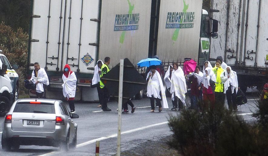 Survivors from a tourist bus crash walk along the highway in the Mamaku Ranges near Rotorua, New Zealand, Wednesday, Sept. 4. 2019. A bus carrying a group of Chinese tourists crashed near a popular New Zealand tourist town. (Ben Fraser/Rotorua Daily Post via AP)