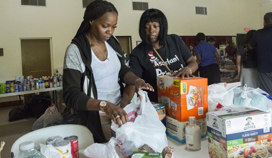 Volunteers Jazz Williams, 29, left, and Jodye Scavella, 47, organize donated goods for those affected by Hurricane Dorian in the Bahamas, at Christ Episcopal Church in Miami, Tuesday, Sept. 3, 2019. Members of two historically black churches are sorting and preparing the supplies to be flown to the hurricane-ravaged islands of Abaco and Grand Bahama. (AP Photo/Ellis Rua)