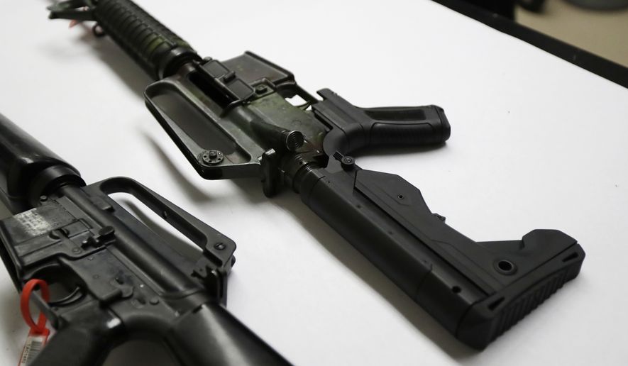 In this Jan. 11, 2018, file photo, a semi-automatic rifle at right that has been fitted with a so-called bump stock device to make it fire faster sits on a table at the Washington State Patrol crime laboratory in Seattle. (AP Photo/Ted S. Warren) ** FILE **